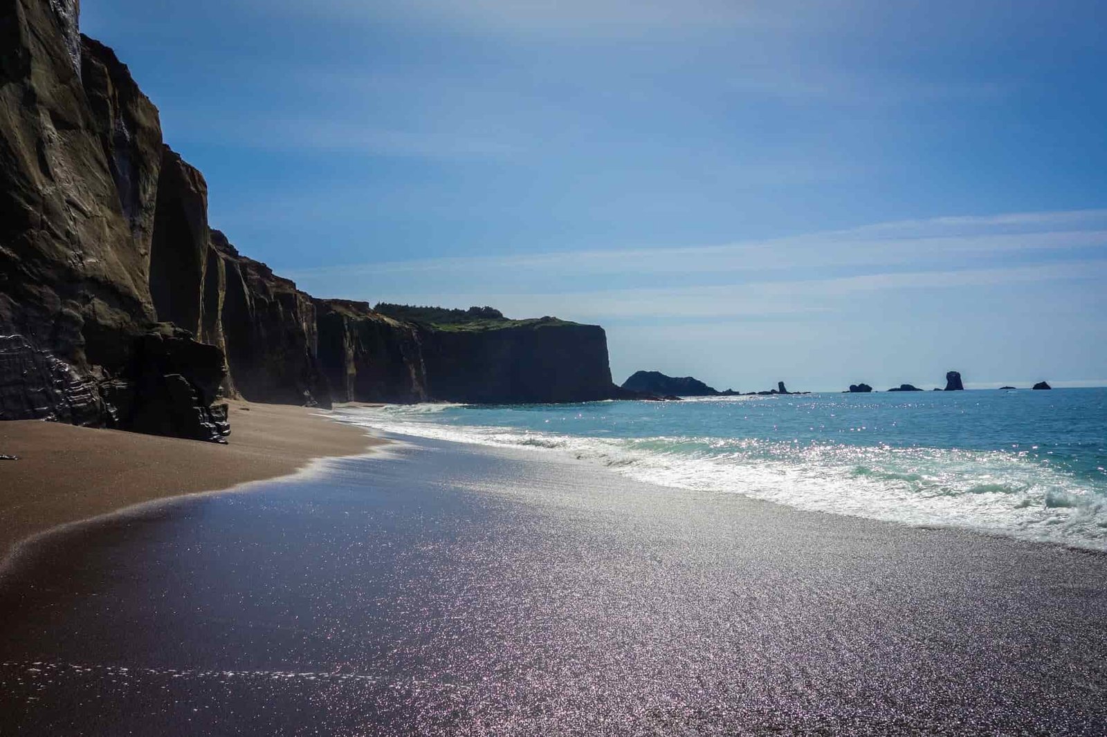 cliffs plunge down to the sandy beach and blue waters of the oregon coast