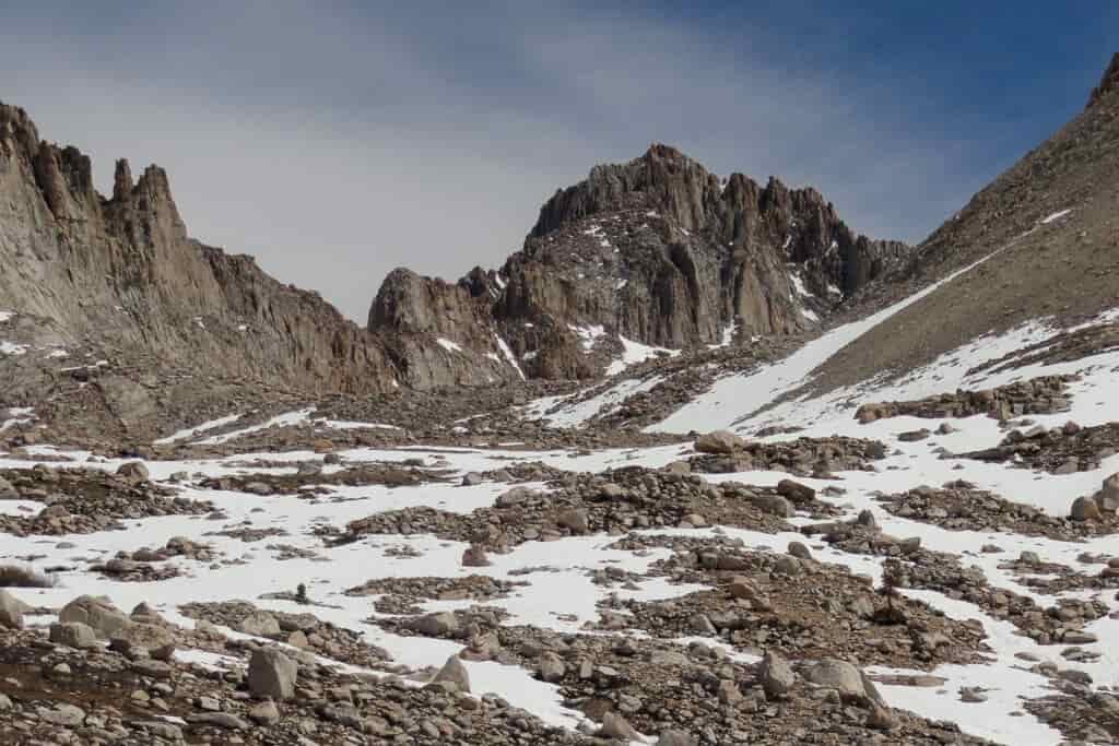 A landscape with rugged gray rocks and streaks of snow