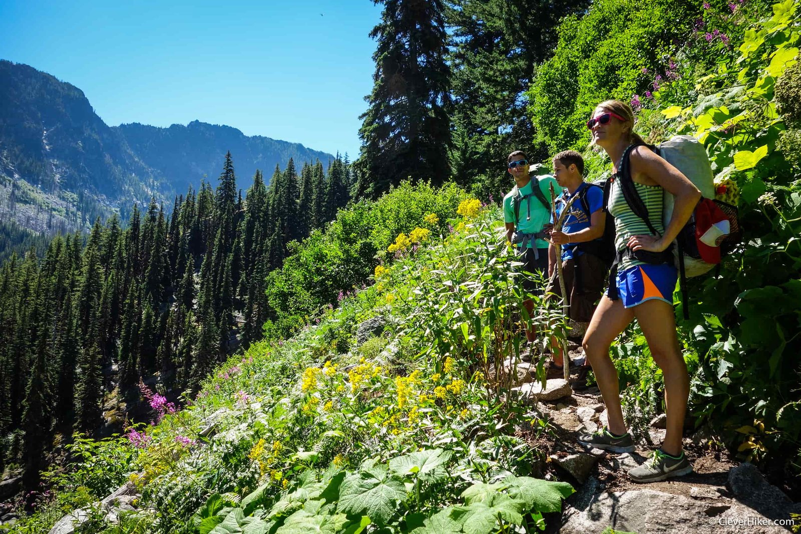 backpackers on a trail pause for a picture heading into the enchantment lakes wilderness