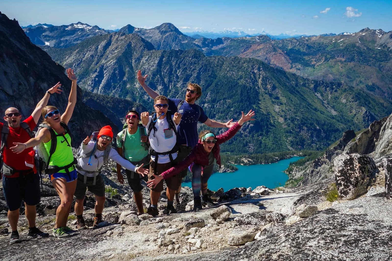friends smiling and posing for the camera atop a mountain pass in the enchantment lakes wilderness