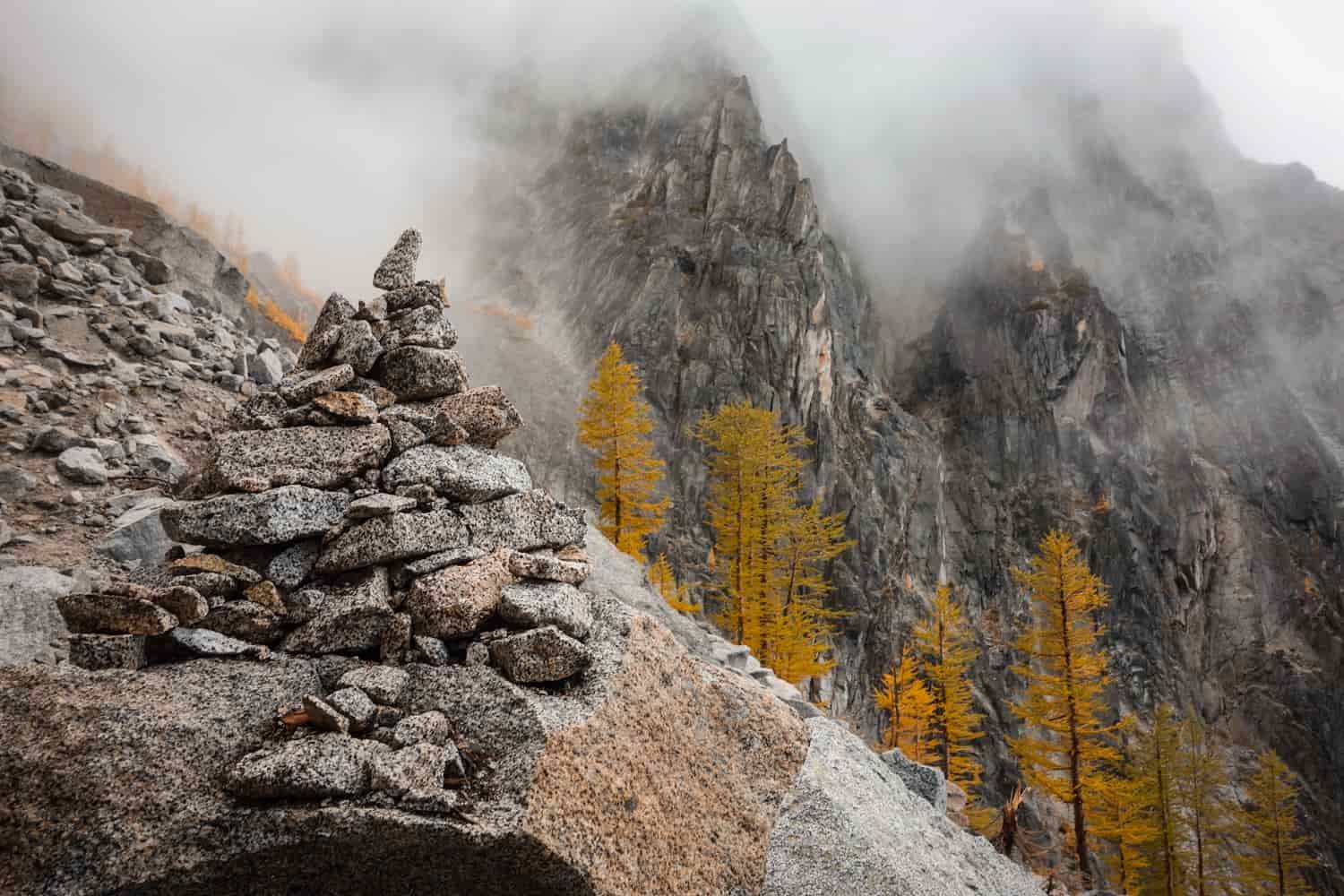 trail cairn in the foreground with misty clounds in the background
