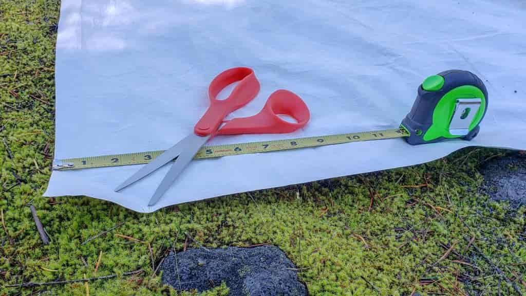 A scissors and tape measure on a sheet of affordable tyvek