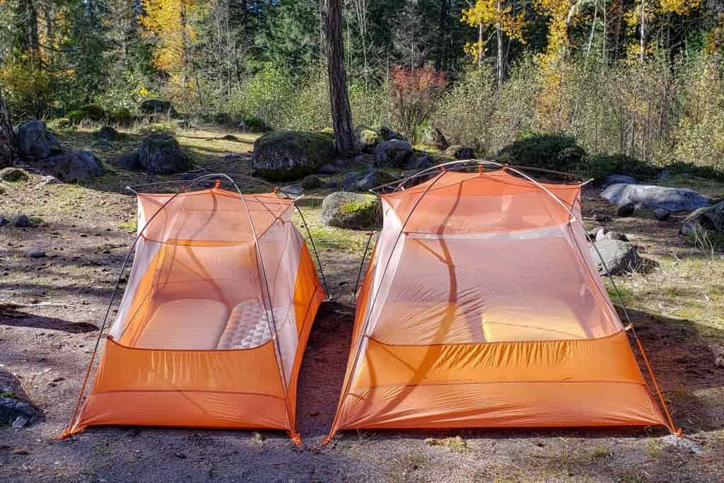 The same model of tent in a 2-person and 3-person sit side by side with sleeping pads inside to show the 3-person leaves small room for gear inside the tent while the 2-person does not