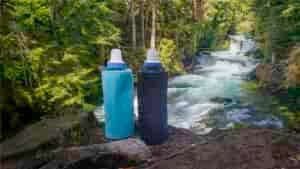 Blue and black HydraPak Flux water bottles fitted with Katadyn BeFree Water Filters in front of the clear-blue McKenzie River