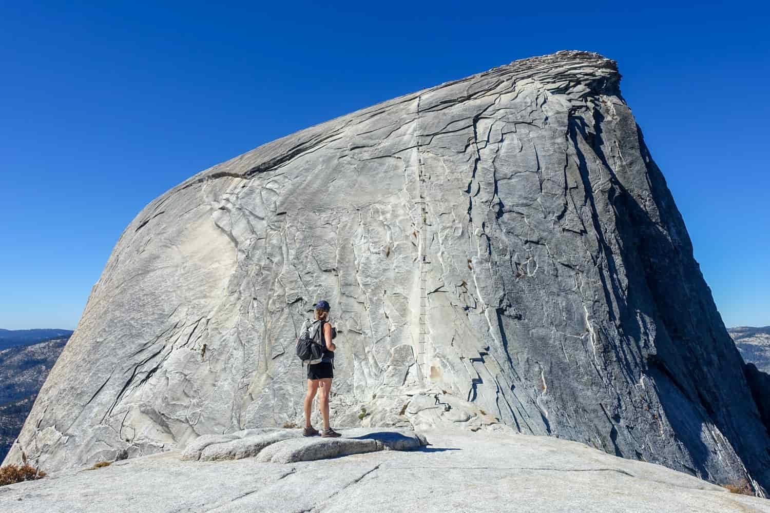 hiker on the subdome of half dome looking at the cables to the summit