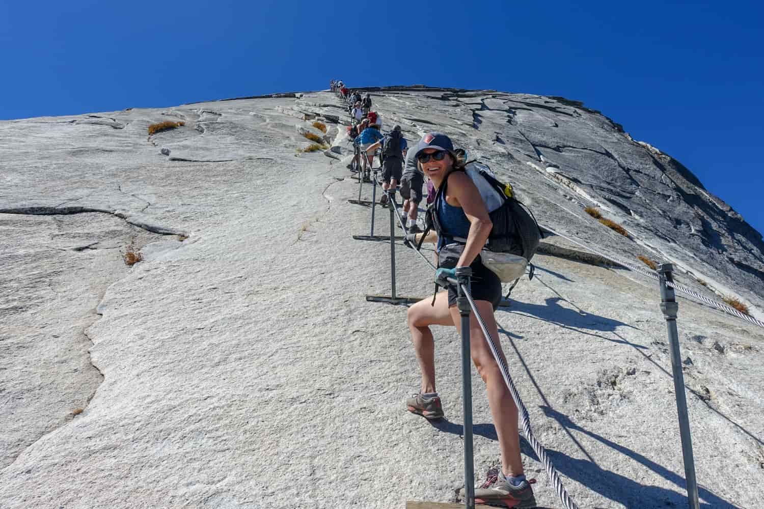 hikers using the cables to reach the summit of half dome