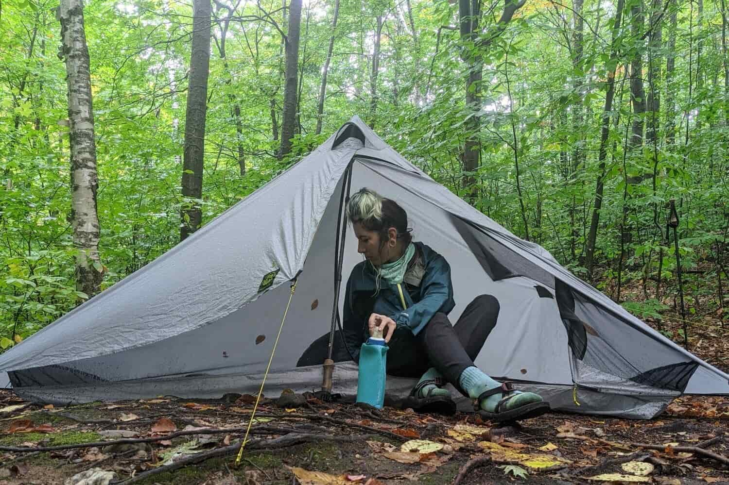 A hiker sitting in the door of the Six Moon Designs Lunar Solo