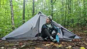 a thru-hiker getting out of their six moon designs lunar solo tent