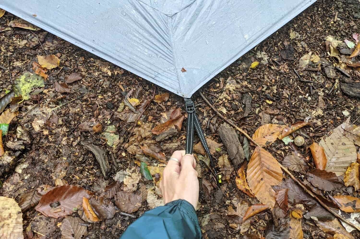 View from above of a hand pulling on the guyout strap of the Six Moon Designs Lunar Solo tent