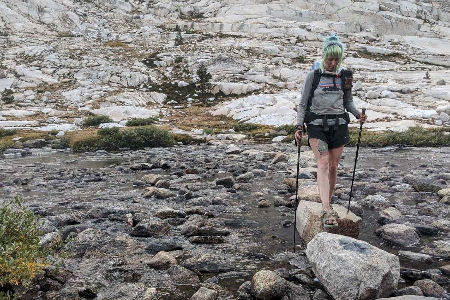 a thru0hiker crossing a rocky stream