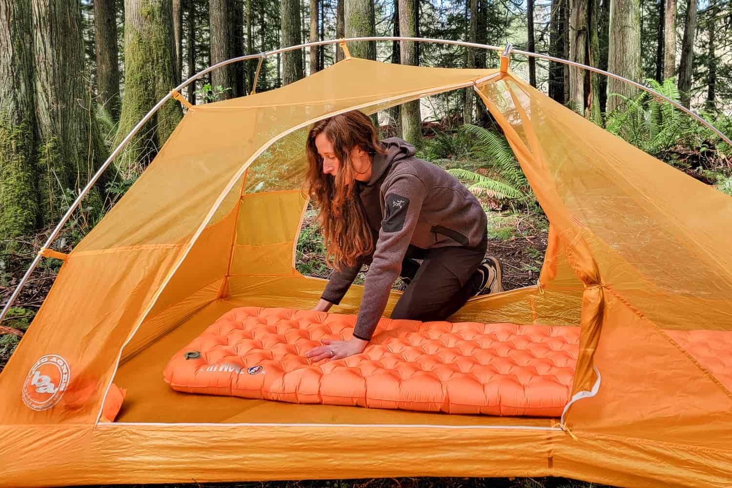 a woman presses her hand on the Big Agnes Zoom Ultralight sleeping pad to show how it holds its shape