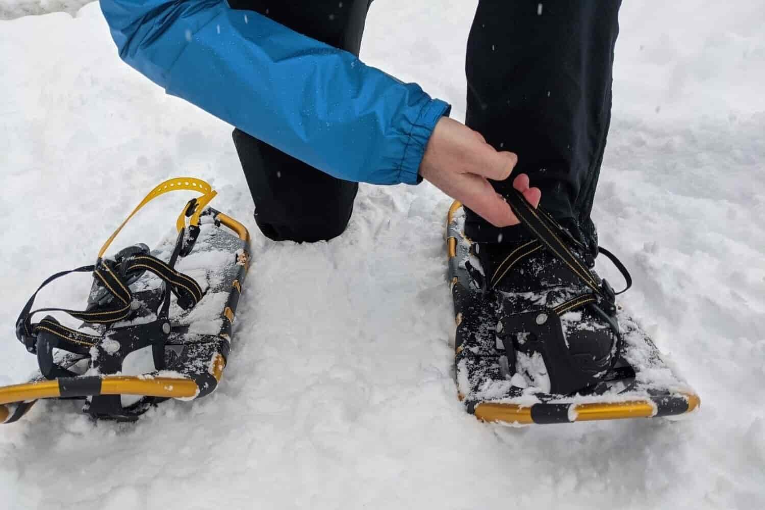 A person adjusting the bindings on the Atlas Montane Snowshoes