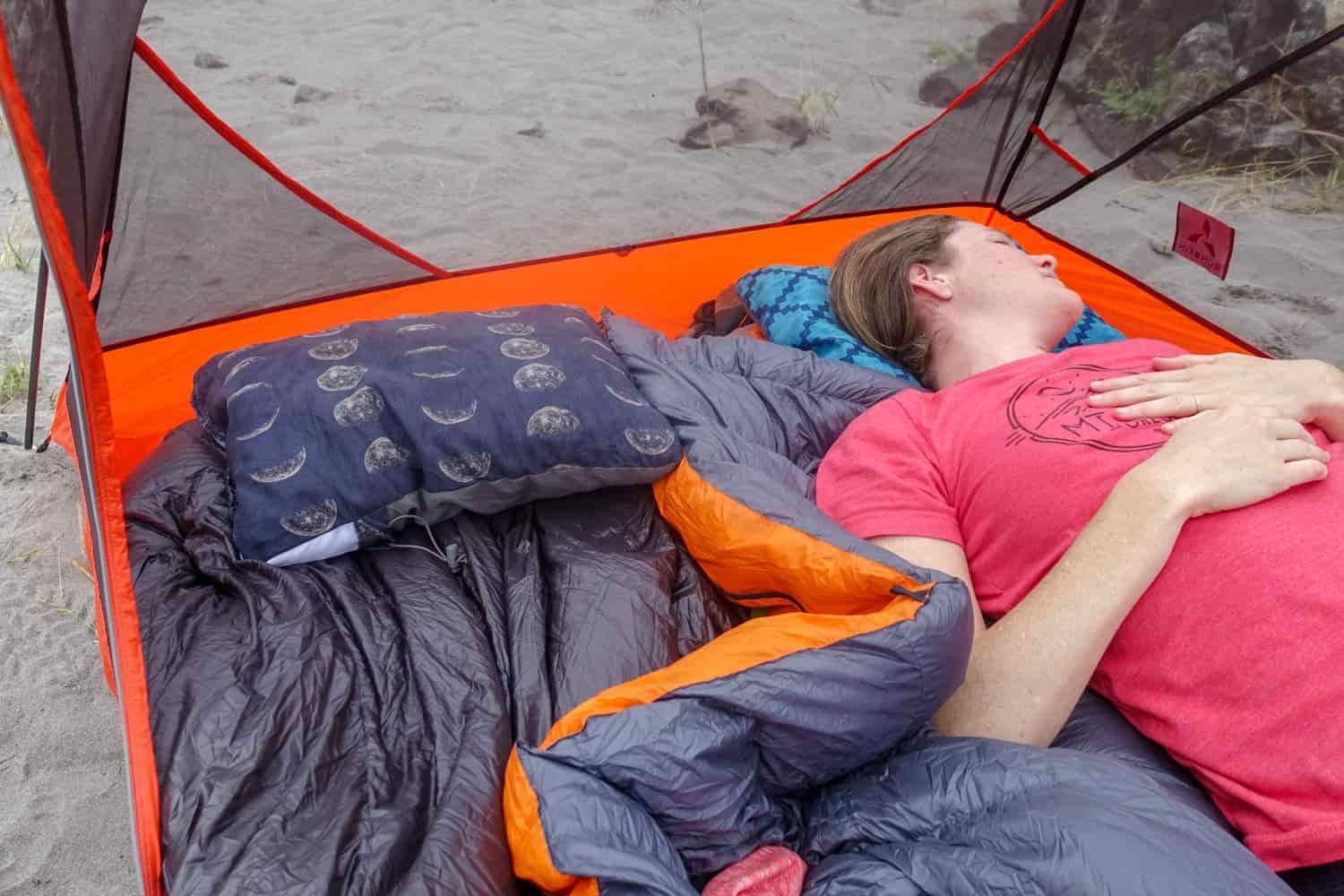 a camper resting in their tent with their head on a camp pillow
