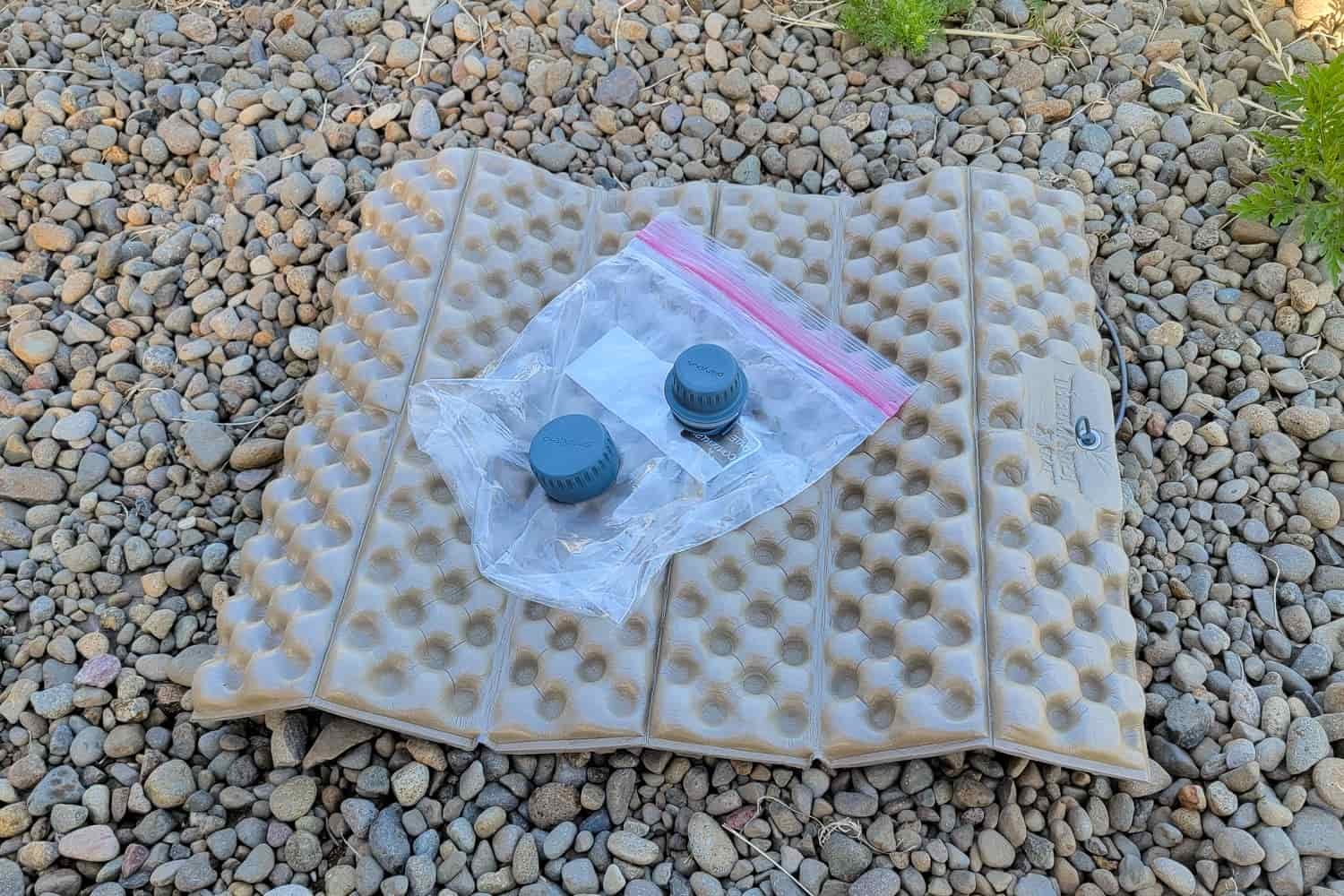 the caps of a platypus reservoir and microfilter on a ziploc bag resting on a foam pad