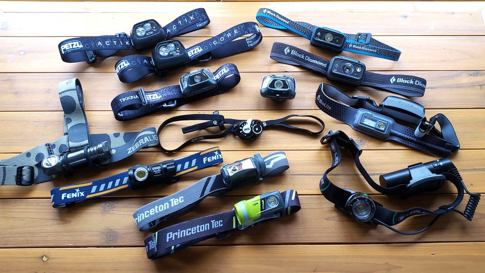 15 backpacking headlamps all on a table on display.