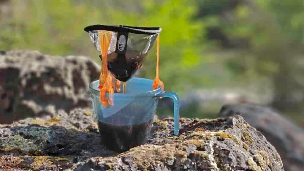 Closeup of the GSI Outdoors Ultralight Java Drip brewing coffee into an ultralight backpacking cup on a volcanic rock
