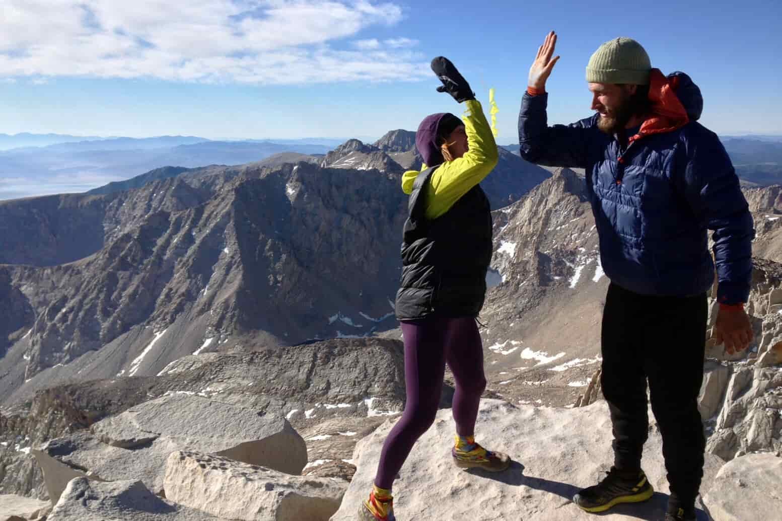 Two hikers high five on the summit of Mt. Whitney