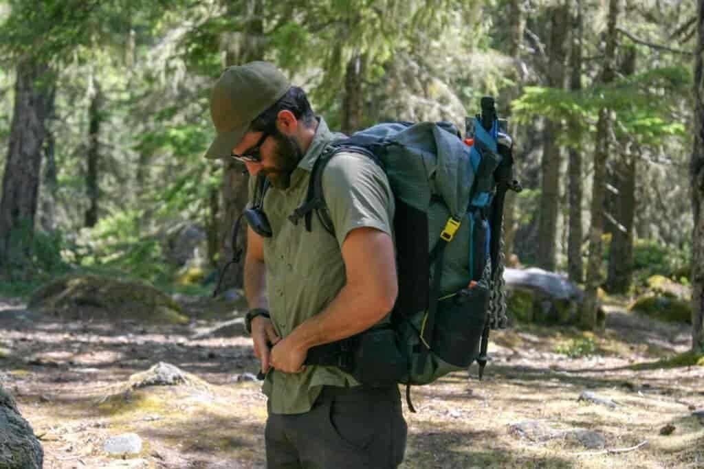 A male hiker tightens the hipbelt on his backpack
