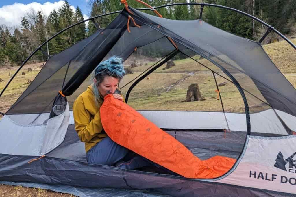 a backpacker inside the half dome two person tent blowing up their sleeping pad