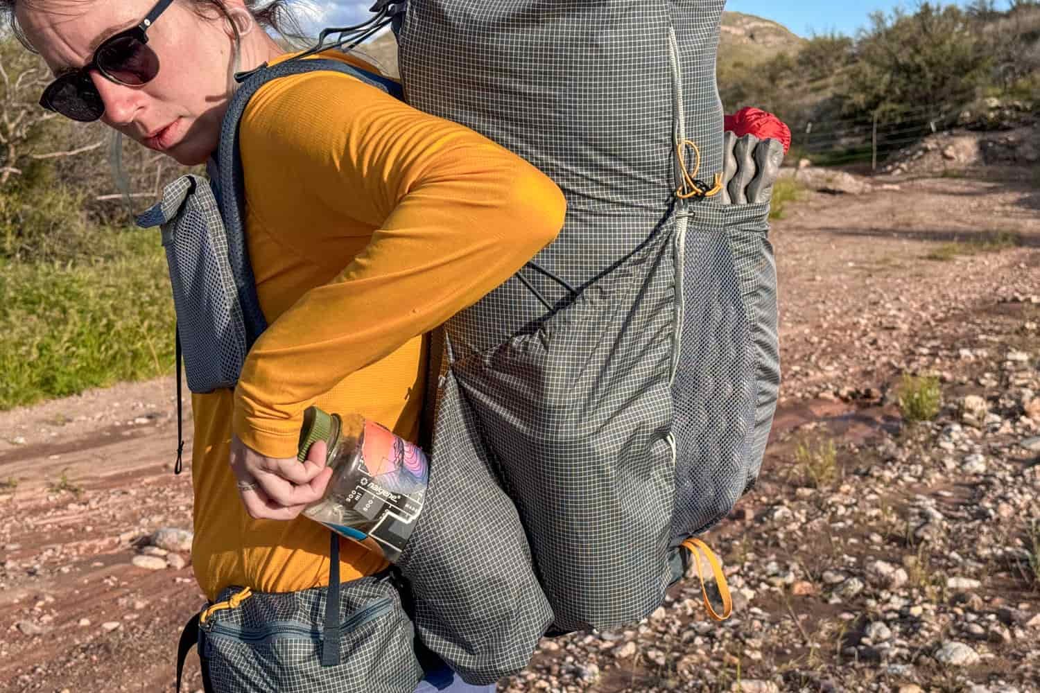 backpacker wearing the ULA circuit and reaching for water from outside pocket