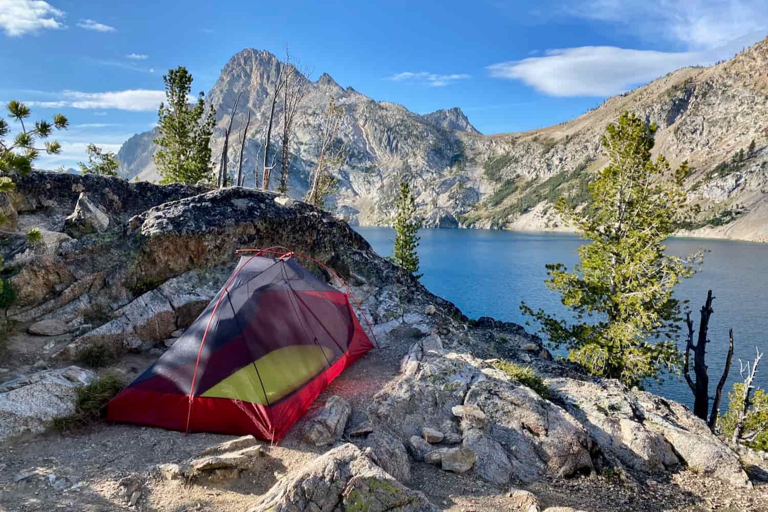 the msr freelite tent set up in a small flat pad between rocks near an alpine lake