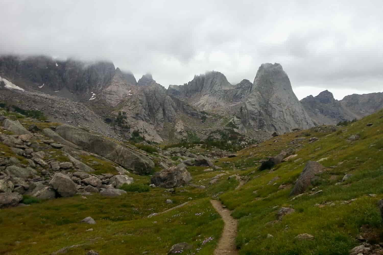 trail leading to rocky mountain tops in a foggy low clouds