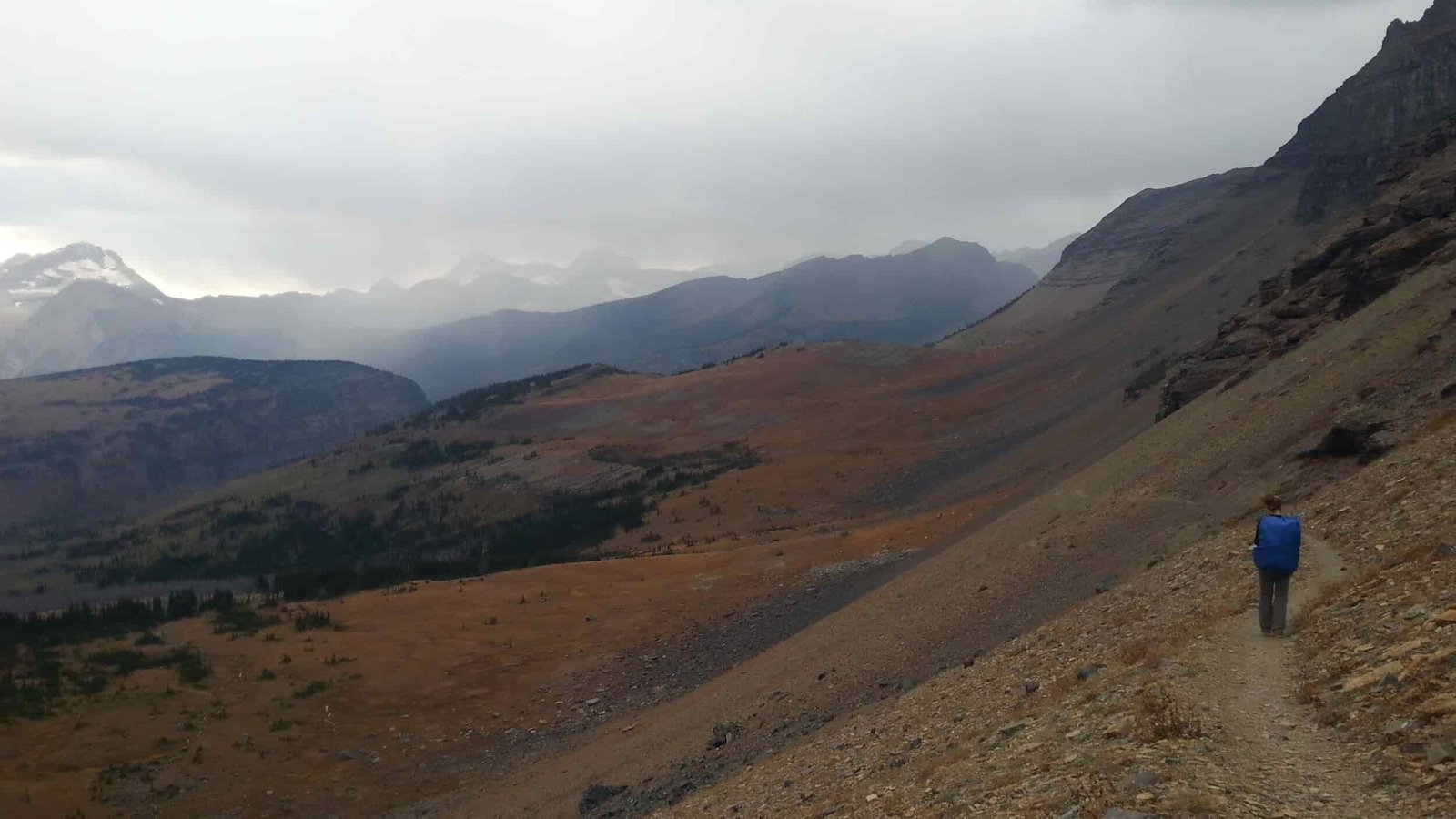 backpacker on the Continental Divide Trail in a treeless mountain landscape with rain clouded skies