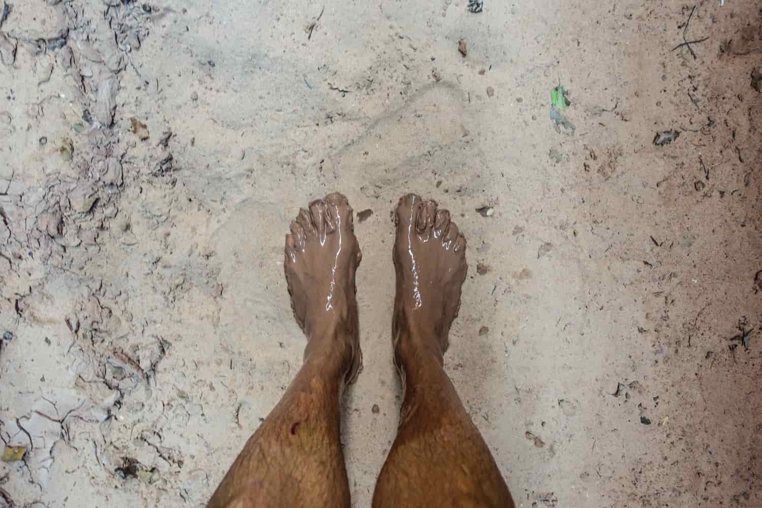 a view of a hikers legs from the knees down to show how muddy his feet are