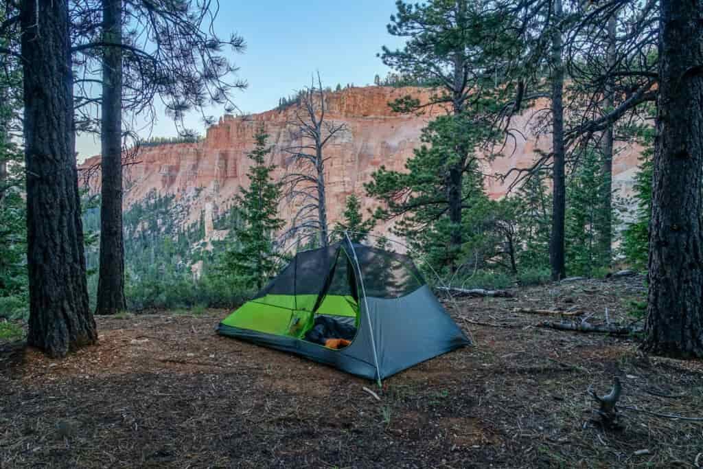 A tent perched under spruce trees with a scenic overview of pink rock cliffs at Bryce Canyon