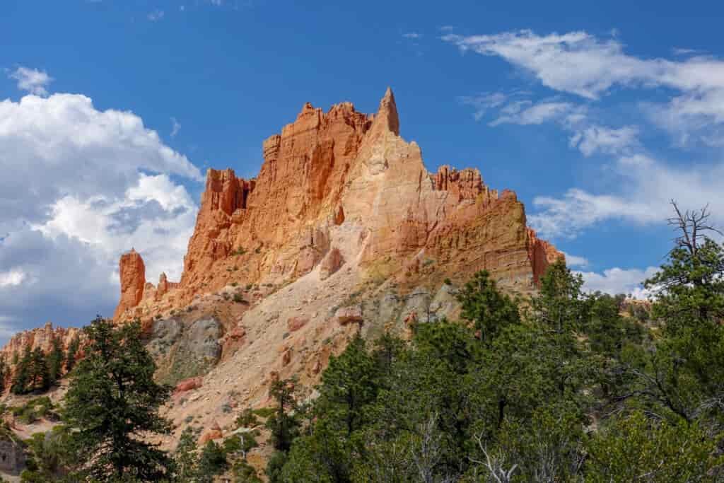 A scenic shot of red mountain with jagged spires pointing towards the blue sky