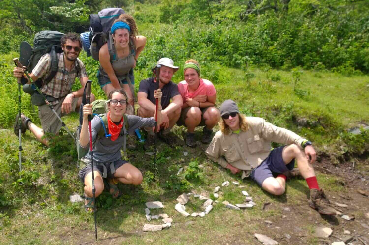 Appalachian Trail thru-hikers gather around the number 500 made with stones on the ground to celebrate hiking 500 miles.