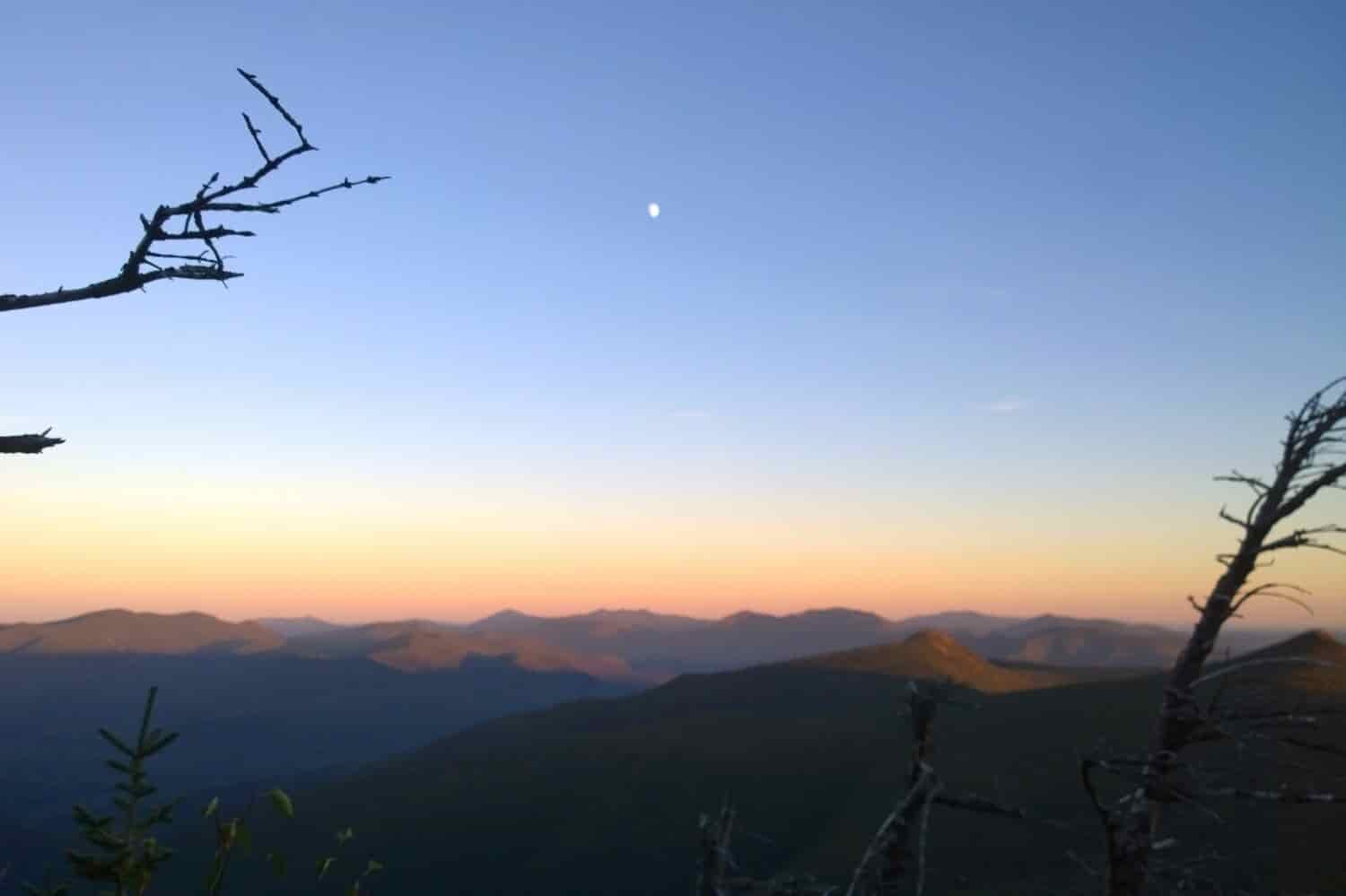 sunset on a mountaintop with the stars and planets starting to shine.