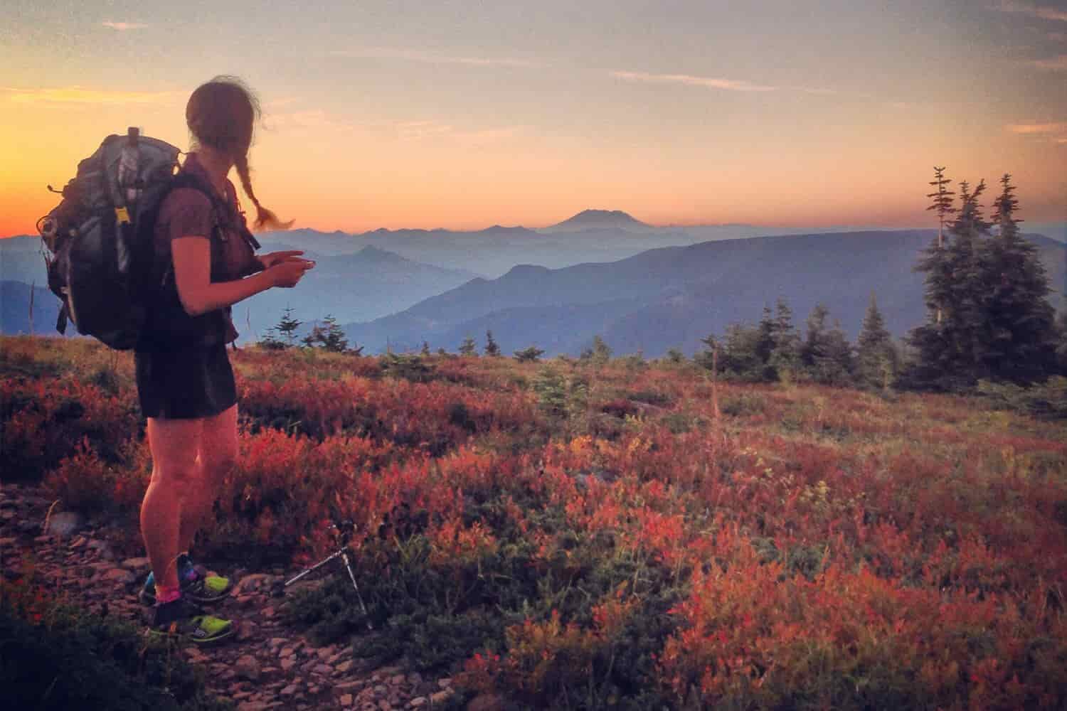 Backpacker on the Pacific Crest Trail watching the sunset over the mountains in the fall.