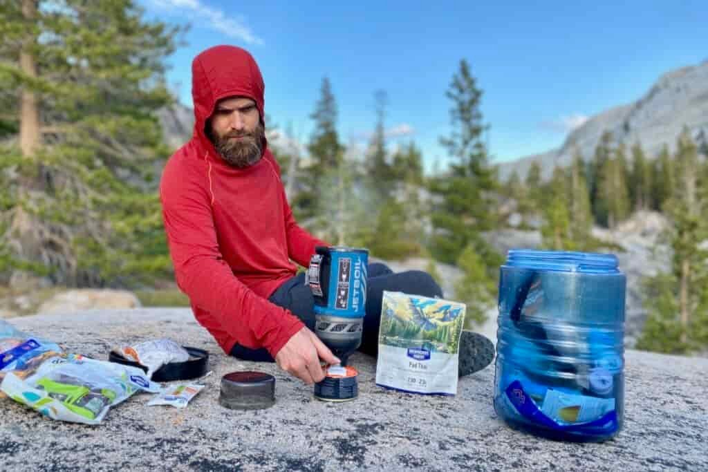 backpacker sitting outside making a meal