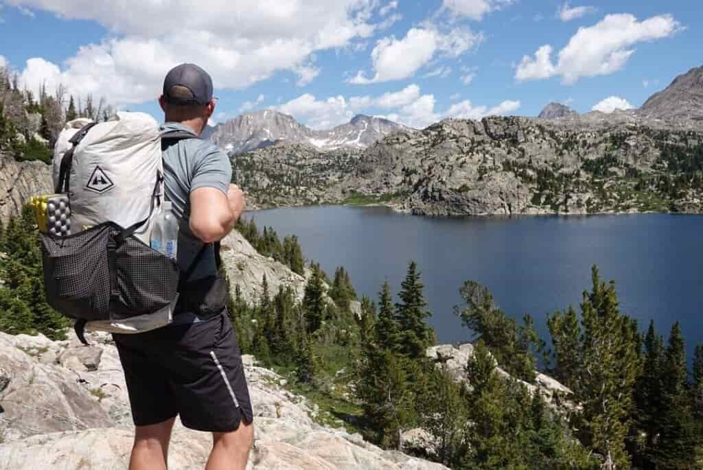 backpacker with his pack on looking at a large lake  