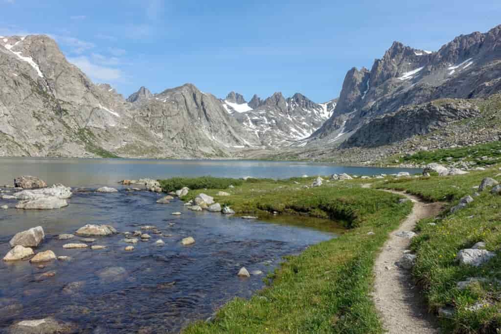 a well worn in path next to a lake in titcomb basin