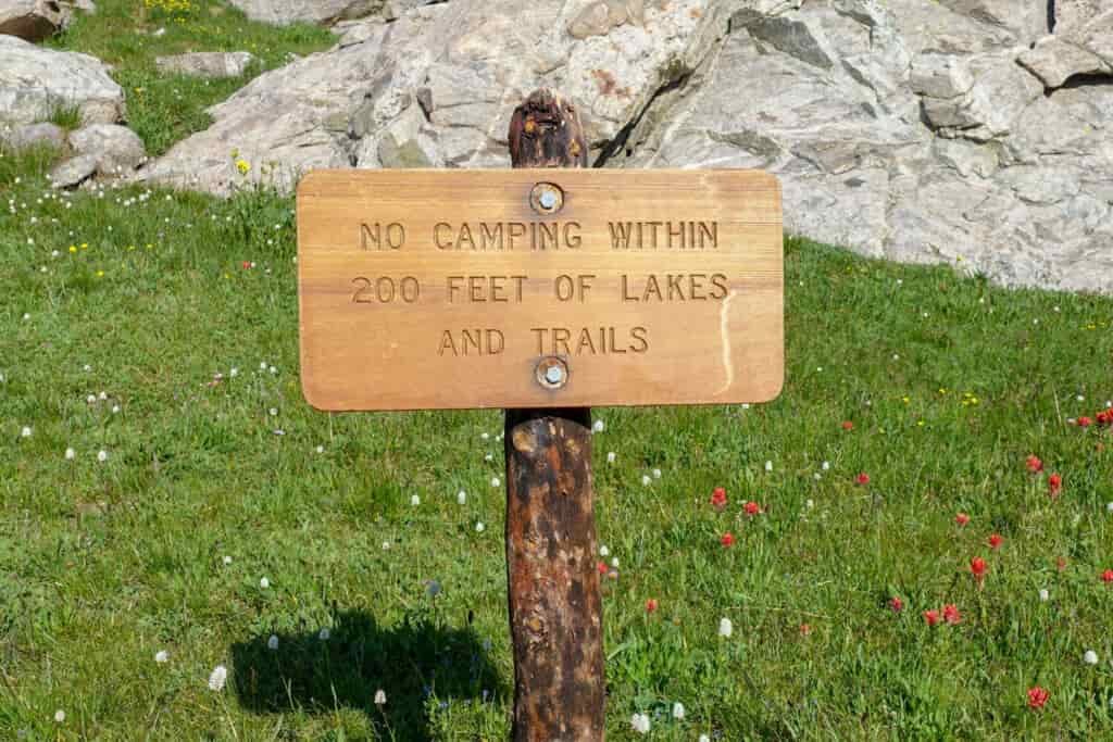 a wooden sign reminding backpackers to camp 200 ft away from water