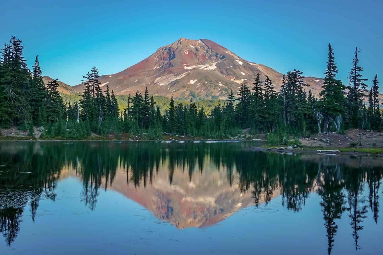 south sister volcano reflected in green lake in oregon
