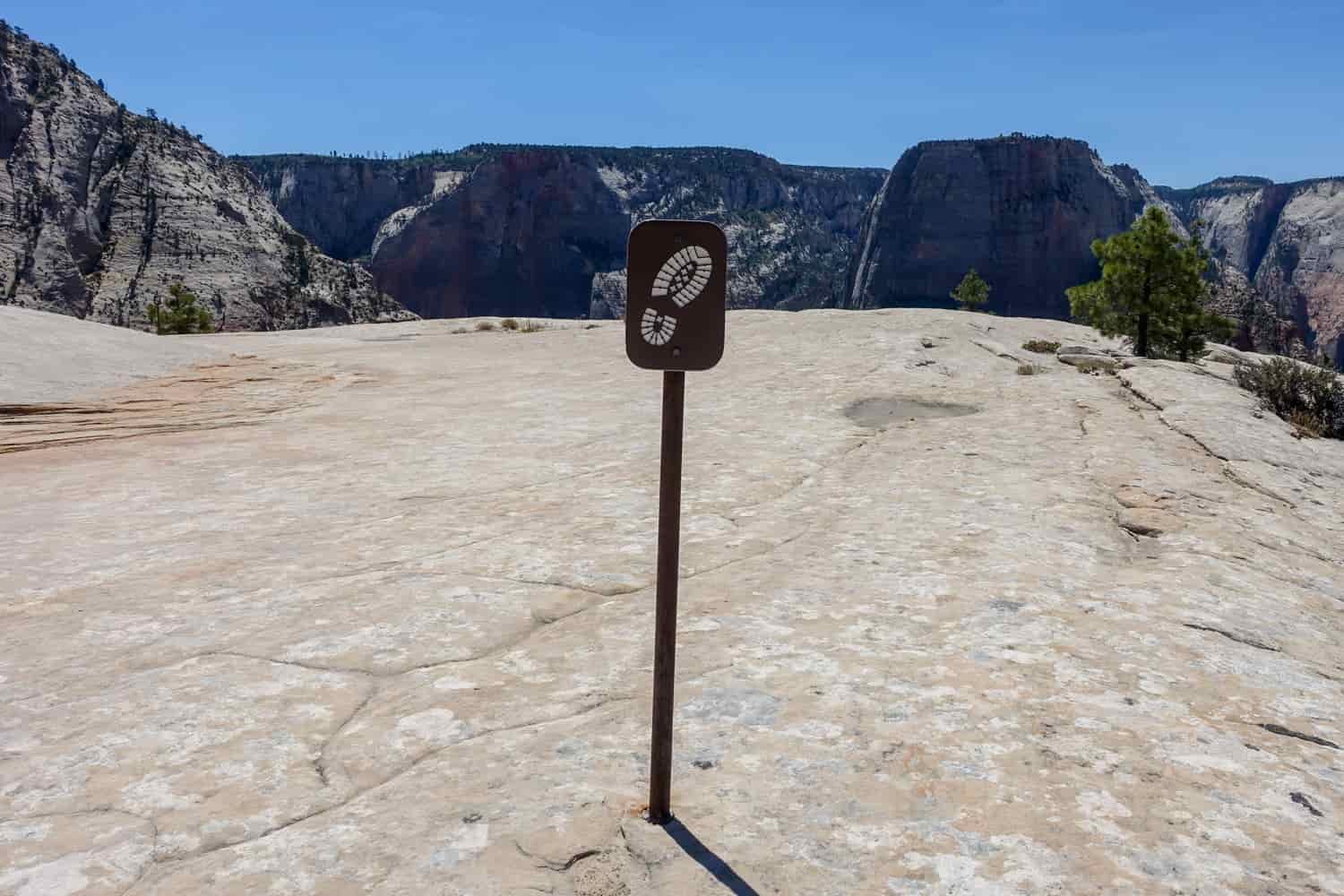 a sign post drilled into white rock to show where the trail is because there isn't any dirt to indicate where people have walked.