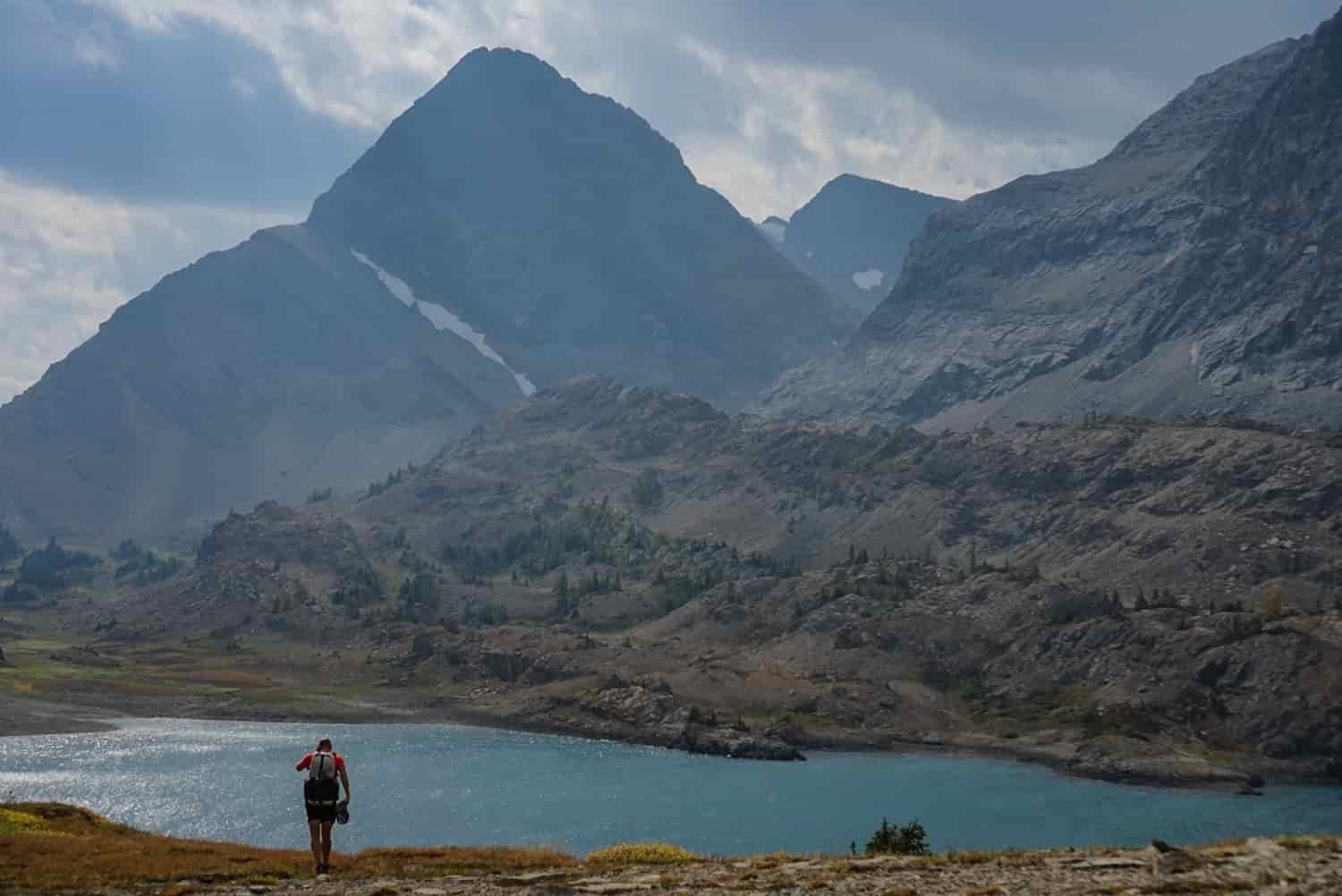 a backpacker above a glacial lake in the mountains