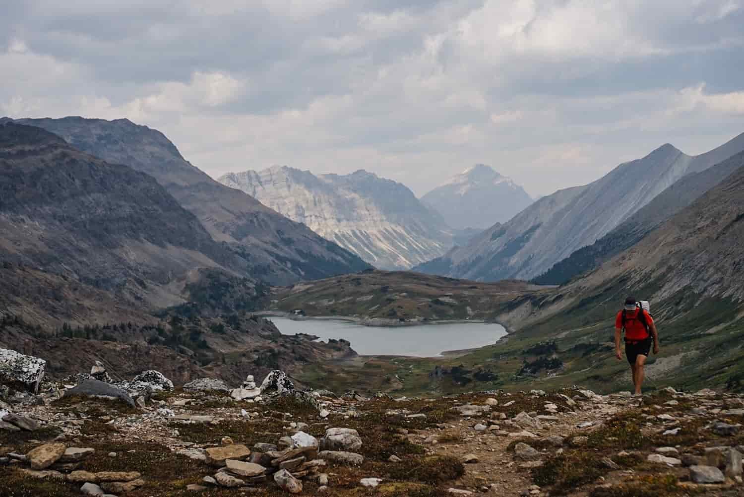 backpacker hiking up a rocky trail out of a glaciated valley
