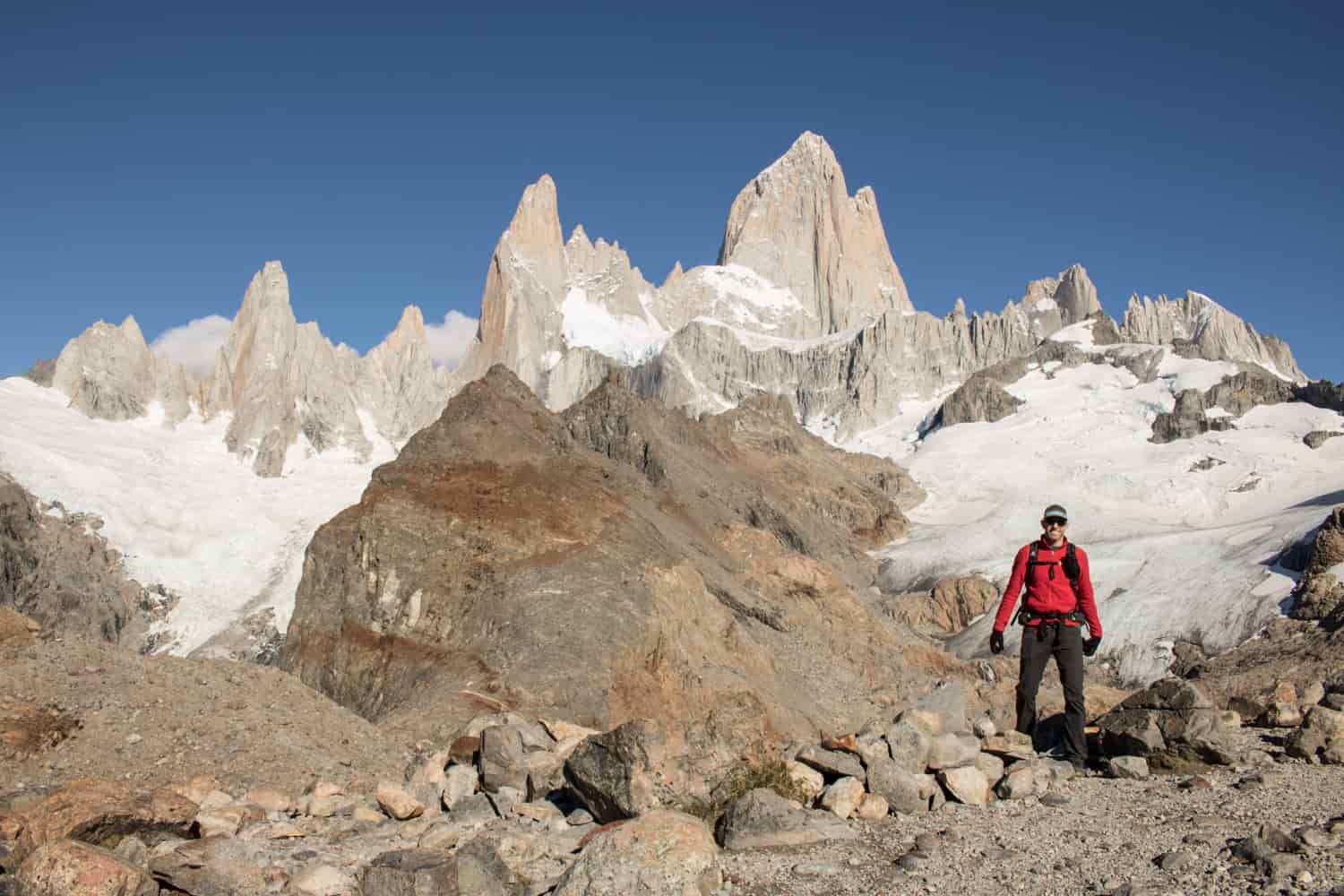 A male hiker poses in front of a glacial snowfield high up in the Patagonian mountains