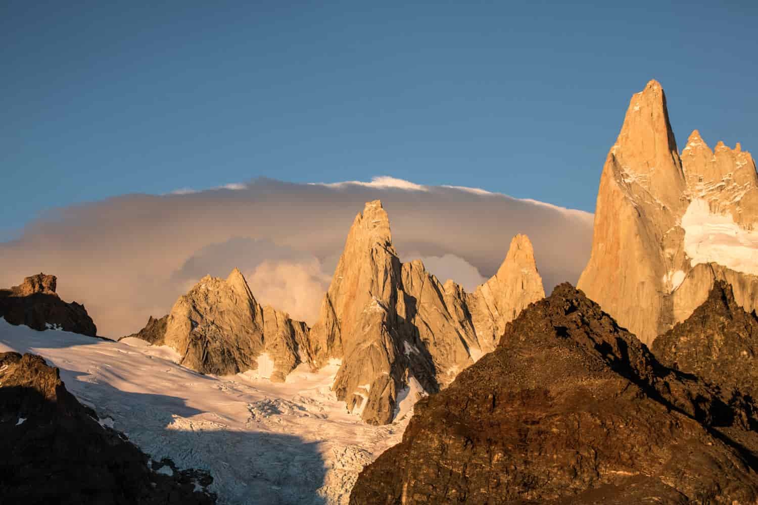 Triangular mountain peaks contrast with the rounded storm clouds in the distance