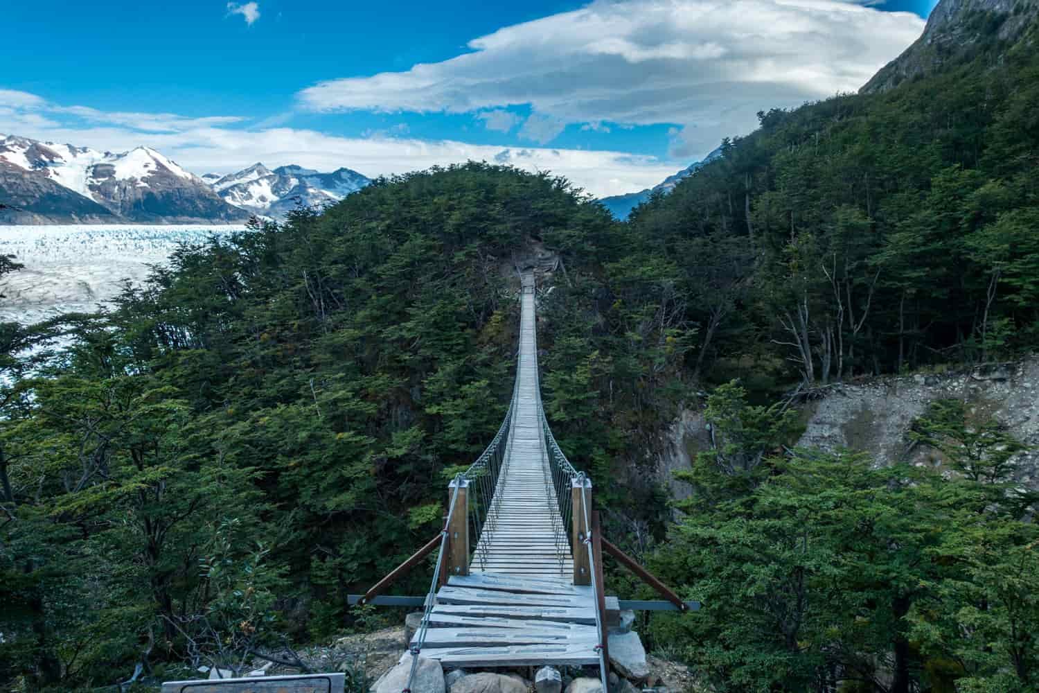 A long and narrow bridge with wood plank footing stretches high above a gorge