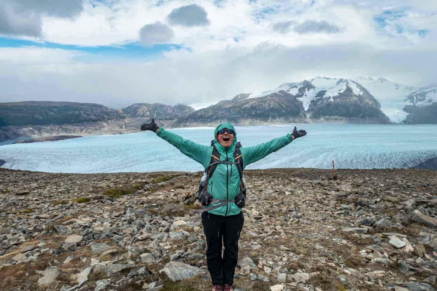 A female hiker poses in front of a glacier
