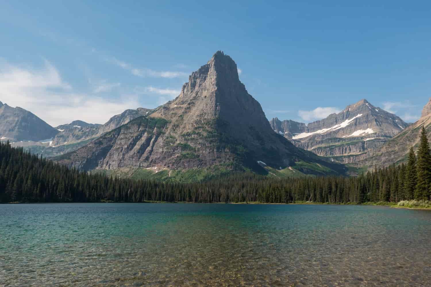 clear blue lake below a rocky mountain in glacier national park