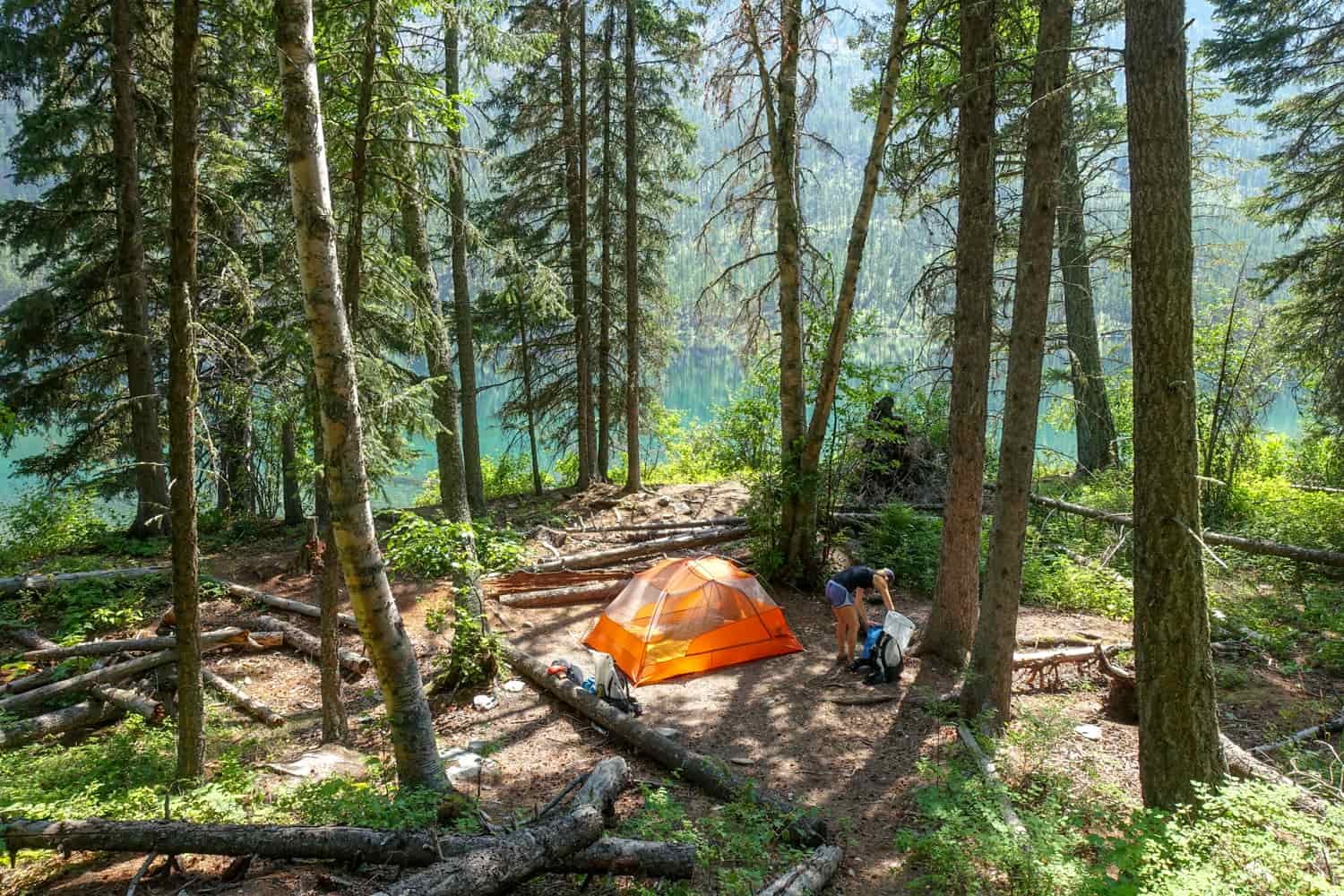 campsite in the forest next to a glacial lake in glacier national park