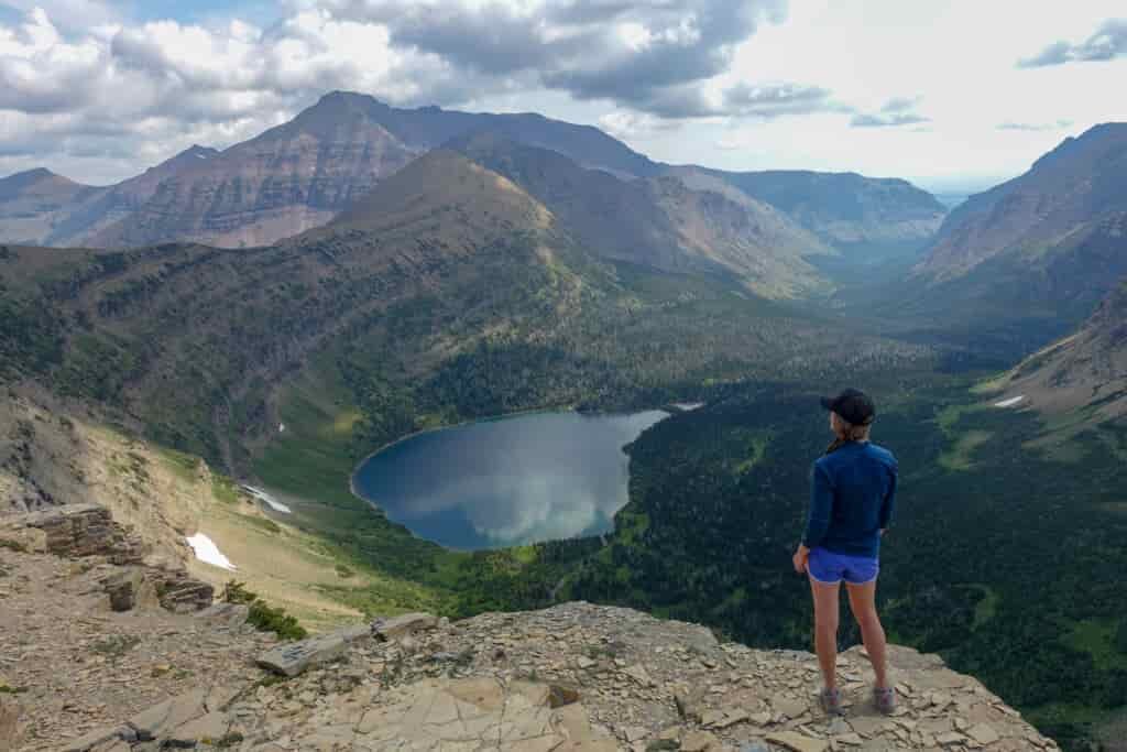 backpacker overlooking a lake enclosed in a ridge in glacier national park