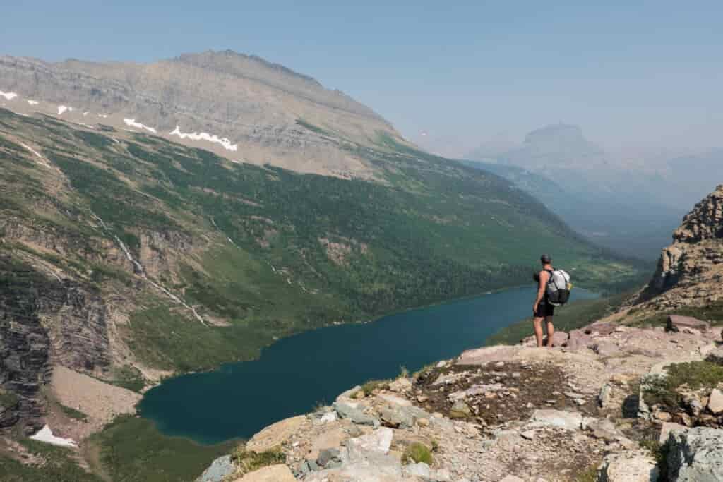 backpacker overlooking lake in a valley in glacier national park