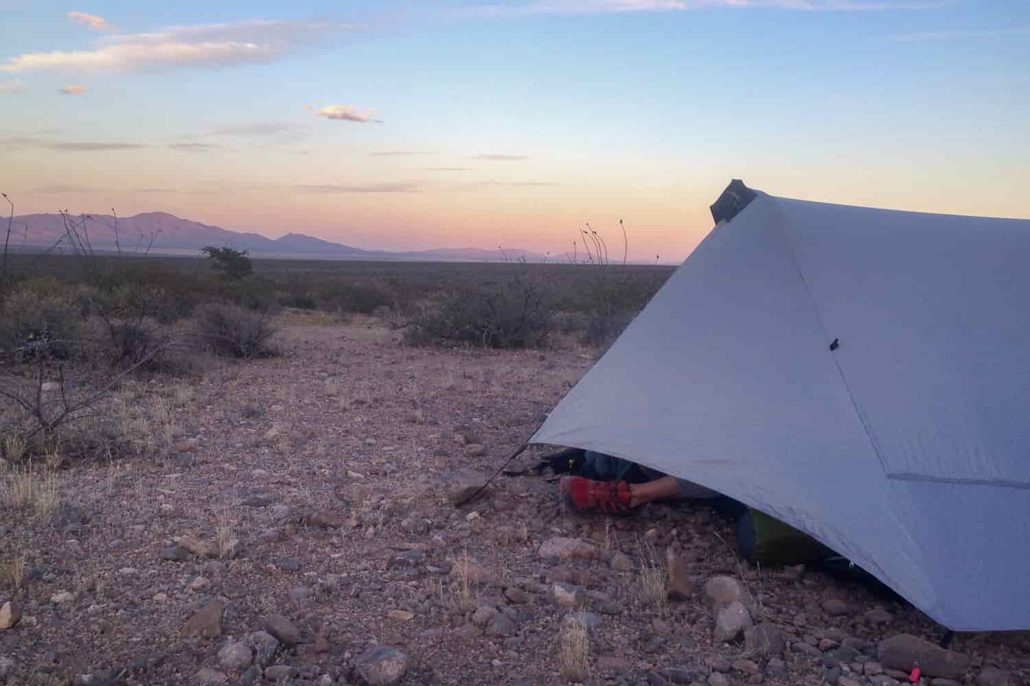 tent set up with the sun setting on high desert landscape